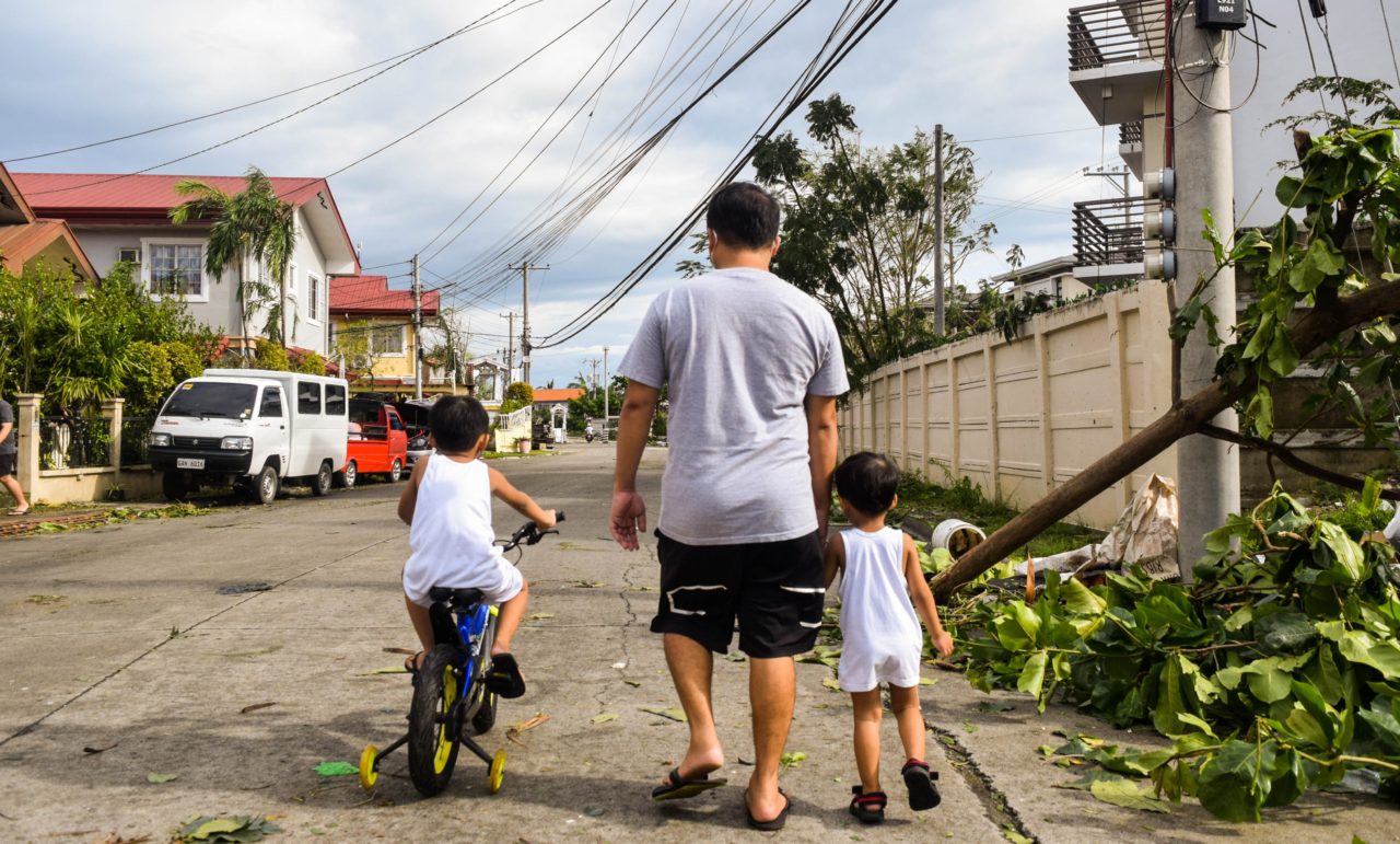 father and two children walk down a street