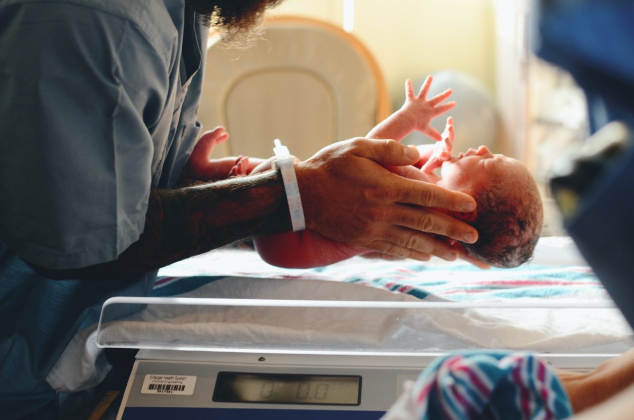 newborn held by nurse