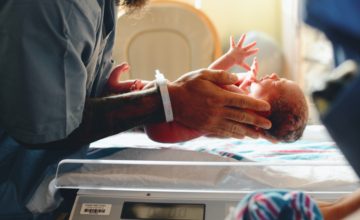 newborn held by nurse