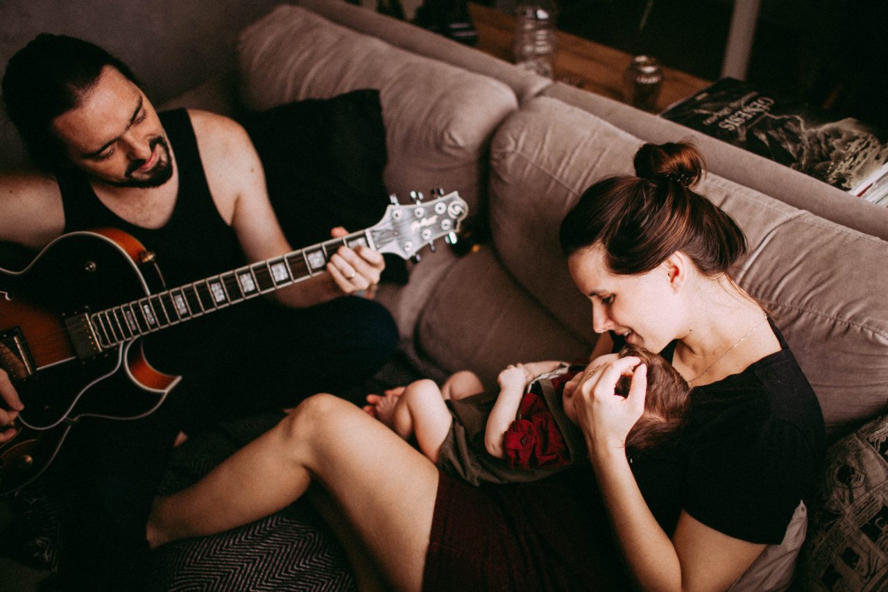 dad plays guitar while mom holds baby