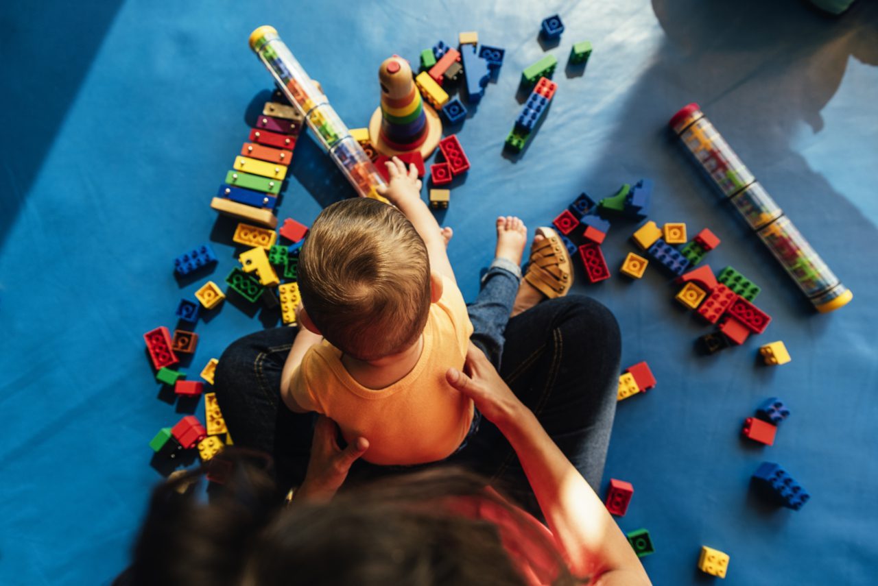 Child sitting in adults lap and playing with Lego toys