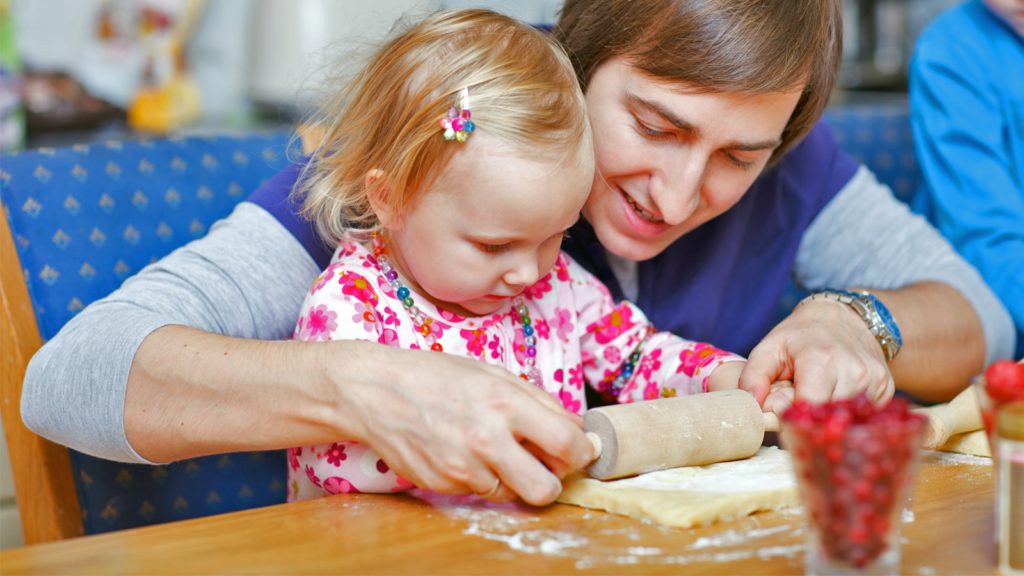 Father and daughter rolling dough