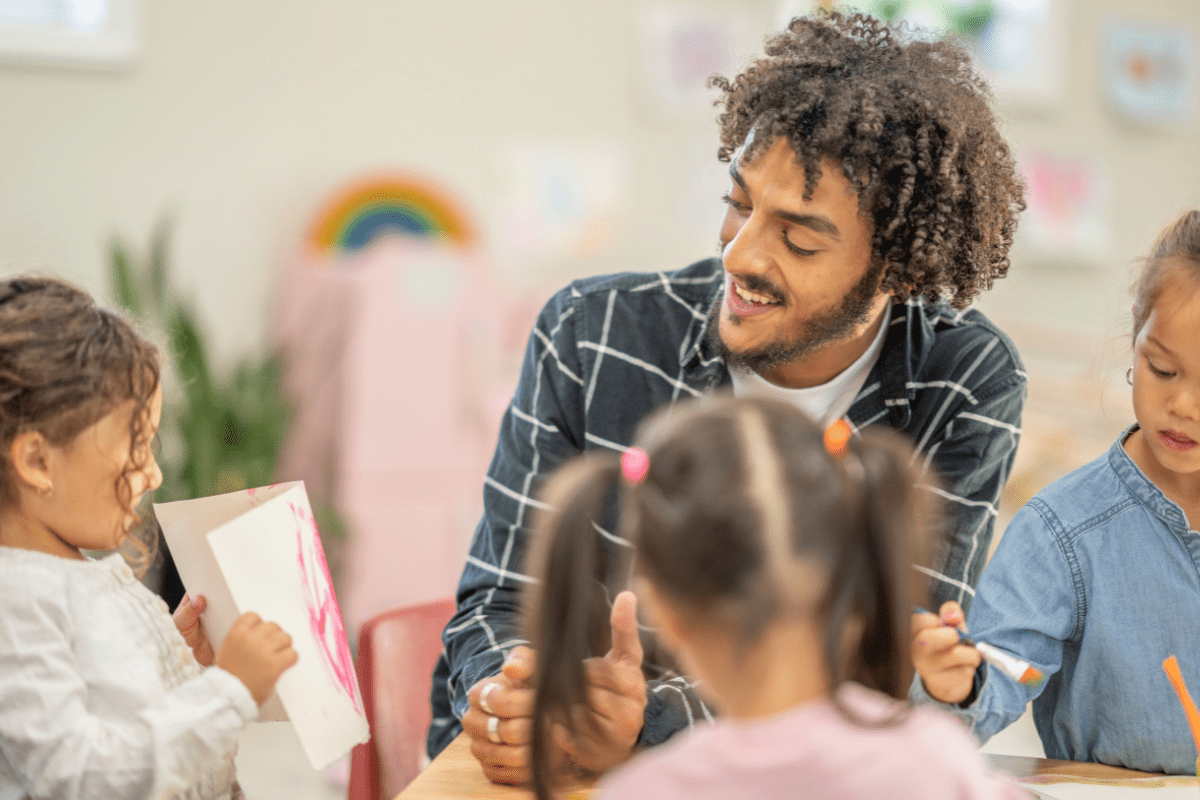 childcare man smiling at kid's drawing