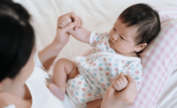 Mom holds baby's hands, asian family