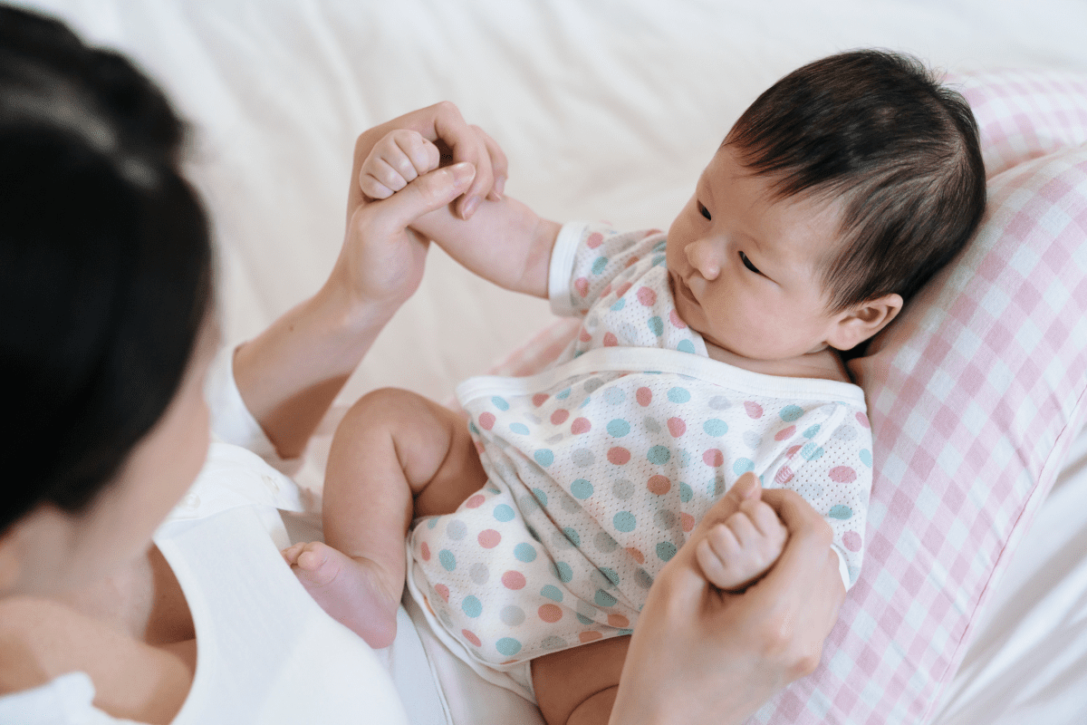 Mom holds baby's hands, asian family