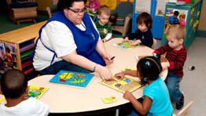 Caregiver does puzzle with kids at childcare