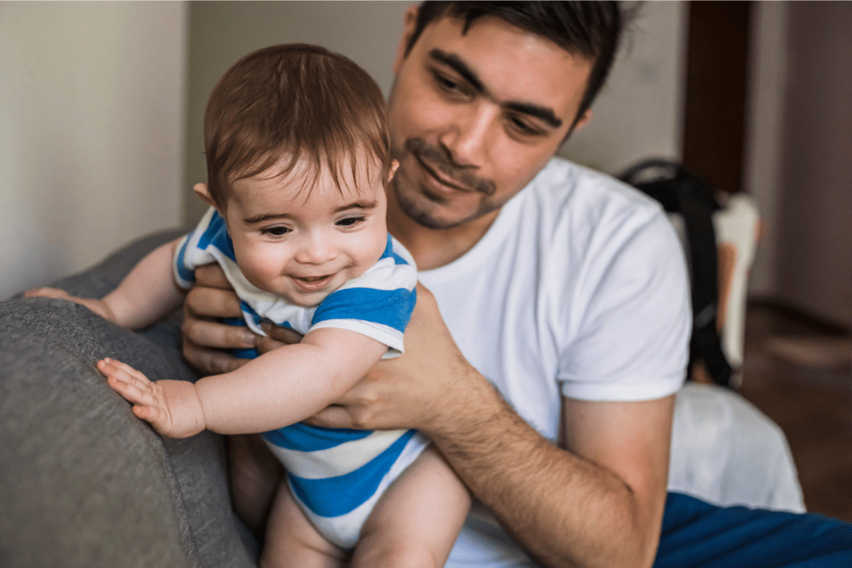 Man holds baby on couch