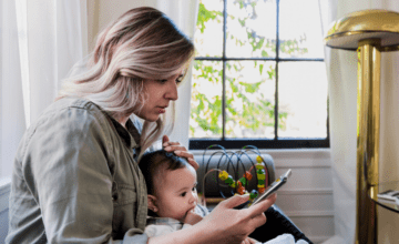 concerned mom holds baby and looks at phone