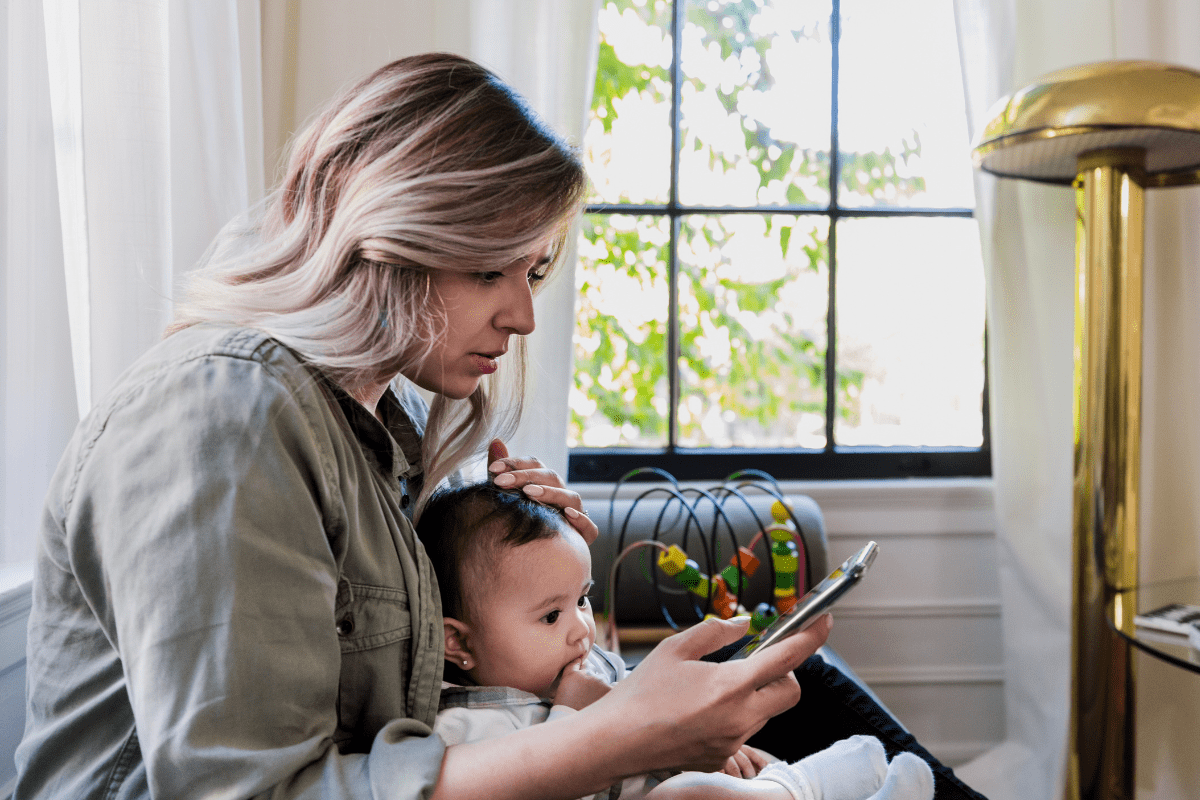 concerned mom holds baby and looks at phone