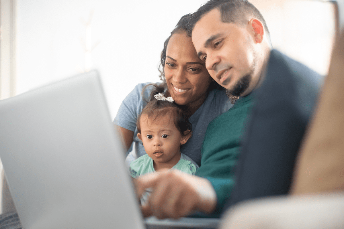 parents look at laptop with baby wearing bow