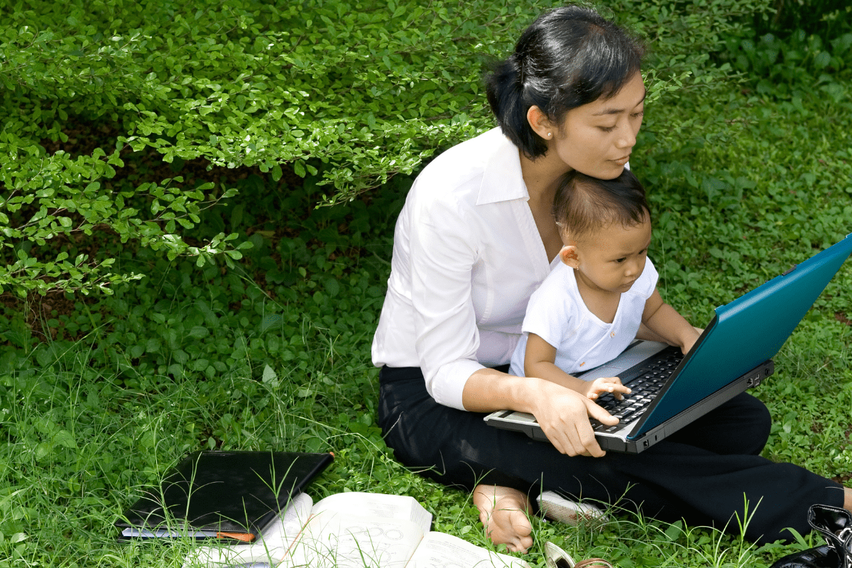 mom and baby look at laptop outside