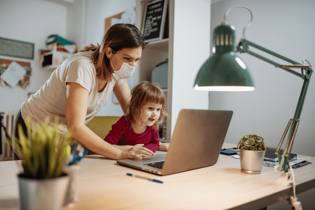 mom wearing mask watches laptop with daughter