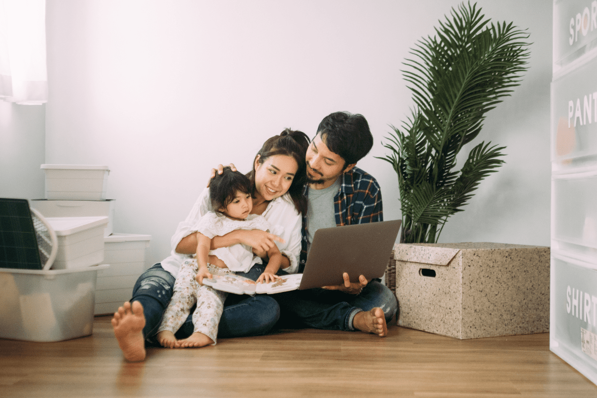 parents and child sit on floor with laptop