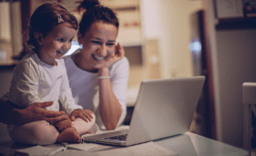 mom and daughter smile at laptop