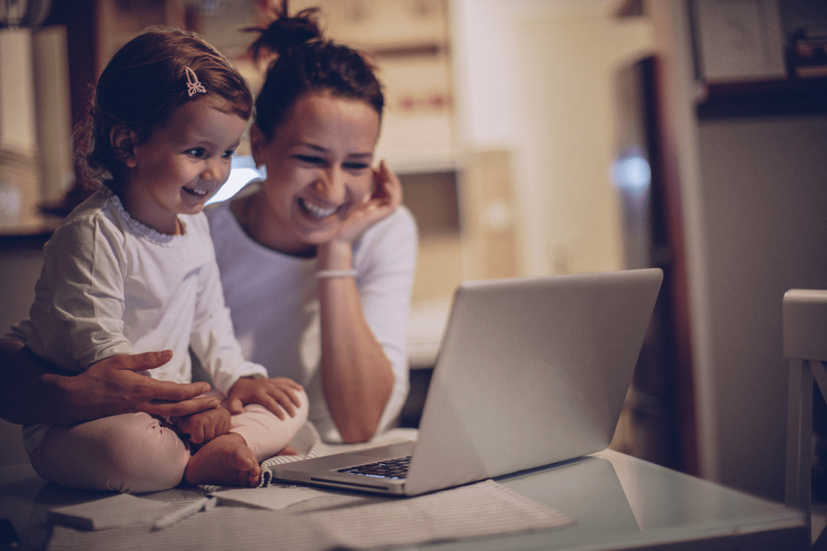 mom and daughter smile at laptop