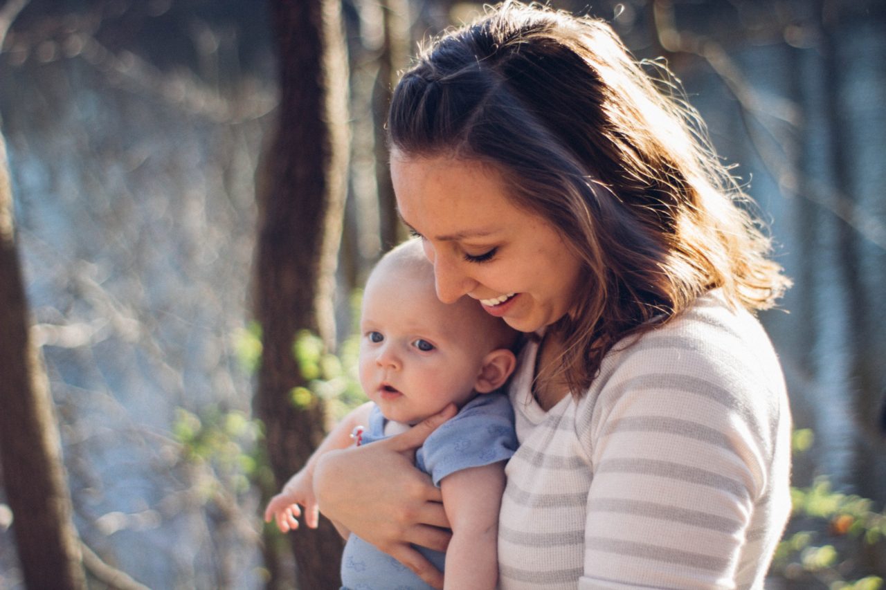 Mom holds baby in forest