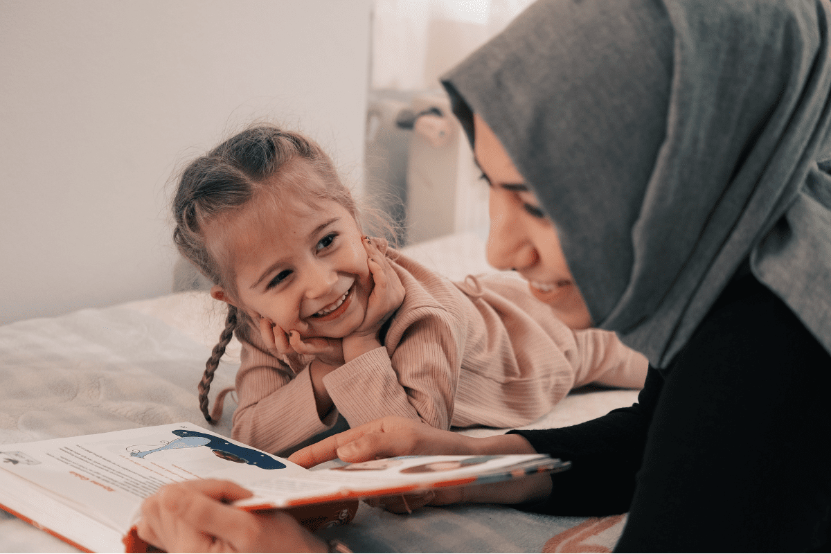 Mother reading book to daughter on bed