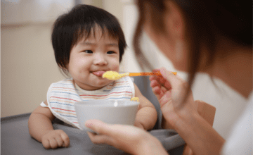 mom feeds baby food with spoon