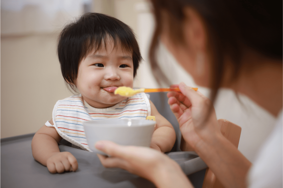 mom feeds baby food with spoon