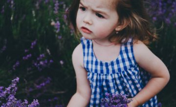 Little girl holding purple flowers walking outside