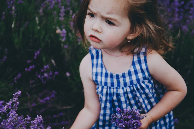 Little girl holding purple flowers walking outside
