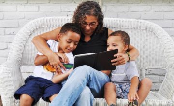 Woman on wicker couch reading to two children