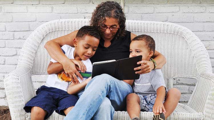 Woman on wicker couch reading to two children