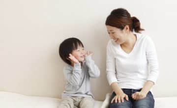 Mother looking at toddler who is playing peek-a-boo