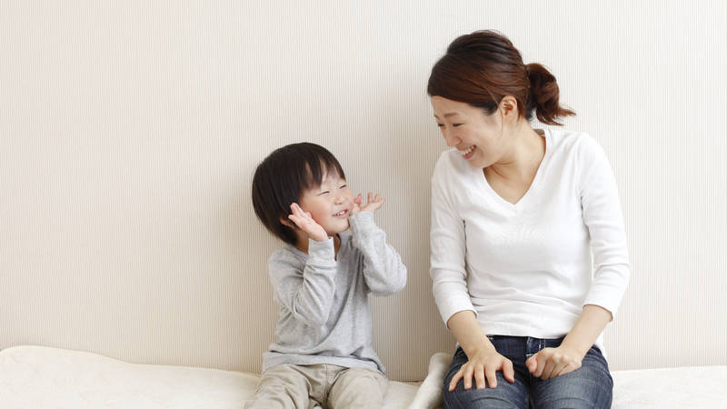 Mother looking at toddler who is playing peek-a-boo