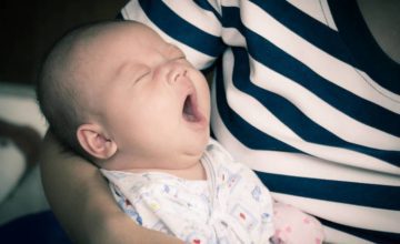 Yawning infant in a person's arms