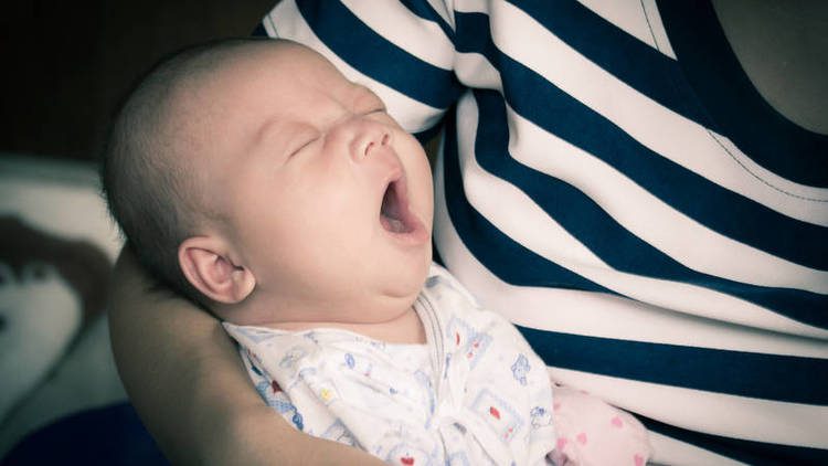 Yawning infant in a person's arms