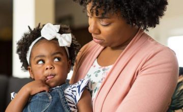 Toddler girl wuth bow in her hair looking at adult woman looking at her