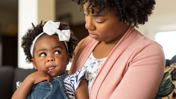 Toddler girl wuth bow in her hair looking at adult woman looking at her