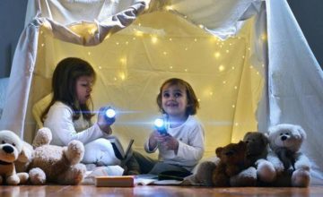 Toddler girls playing in sheet fort