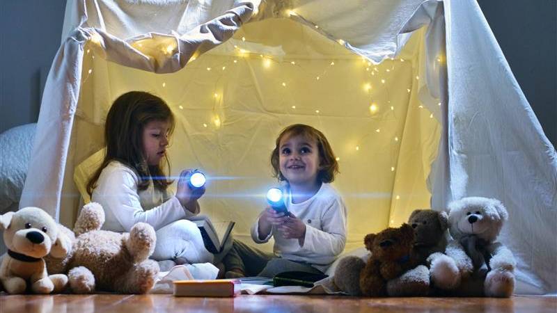 Toddler girls playing in sheet fort