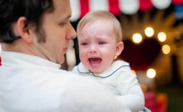 Man carrying crying infant