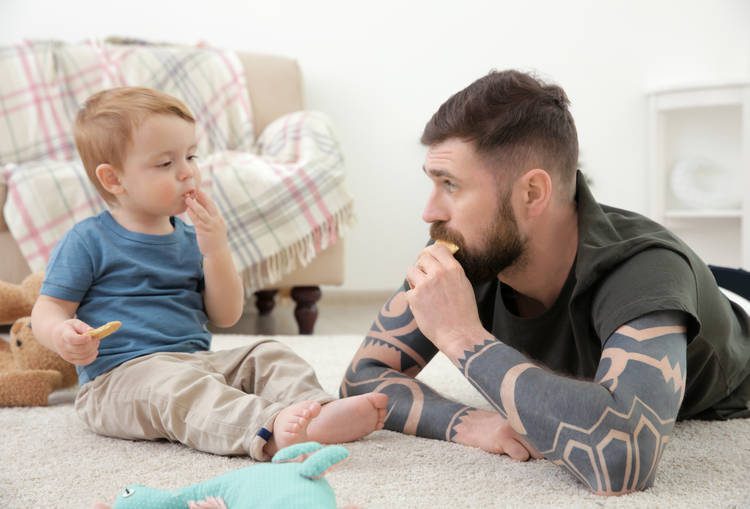 Man an dtoddler looking at each other and eating
