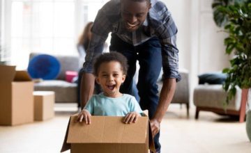 Father pushing toddler son in a cardboard box