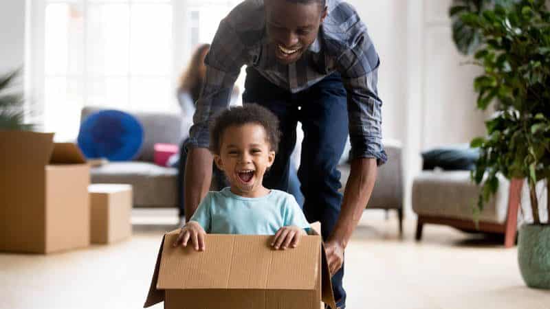 Father pushing toddler son in a cardboard box