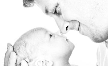 father and infant face nose to nose