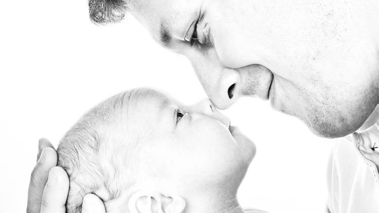 father and infant face nose to nose