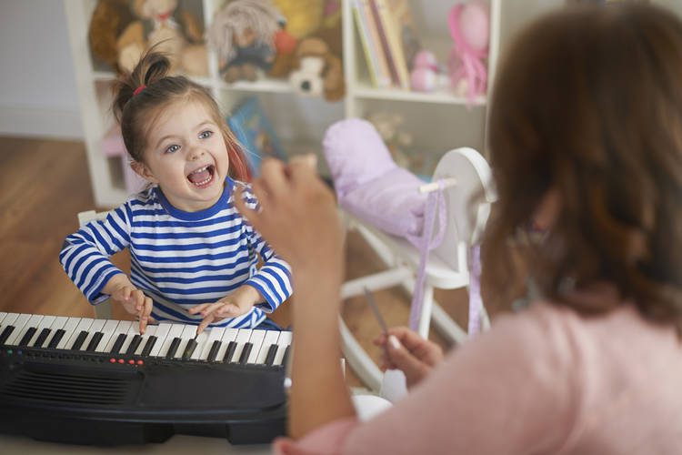 Infant playing keyboard looking at an adult
