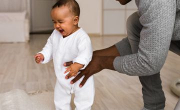 Father helping hold infant stand