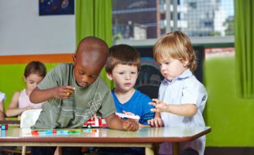Toddlers, 3 boys playing at a table.