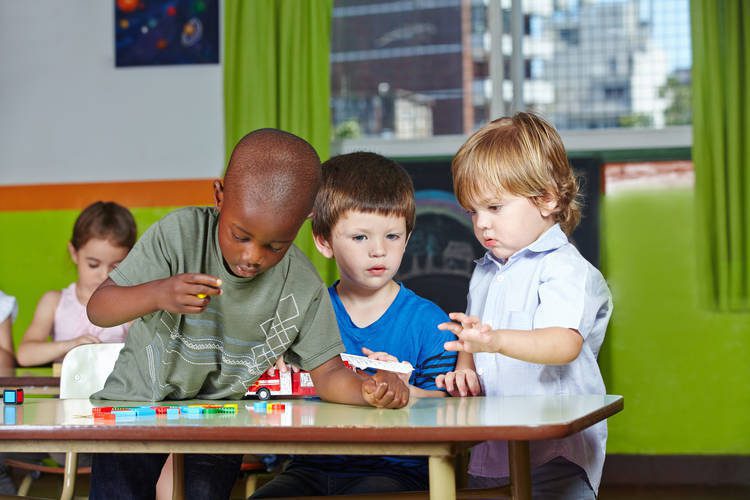 Toddlers, 3 boys playing at a table.