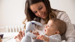 Woman holding toy bunny in front of infant