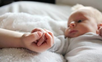 infant holding child's hand