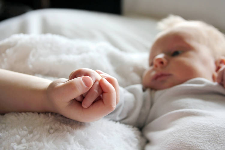 infant holding child's hand