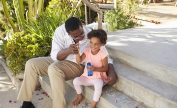 Father daughter with bubble bottle toy and chalk drawing on the floor.