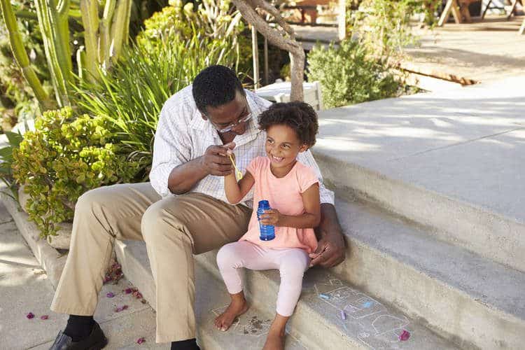 Father daughter with bubble bottle toy and chalk drawing on the floor.